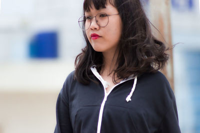 Portrait of beautiful woman standing against blurred background