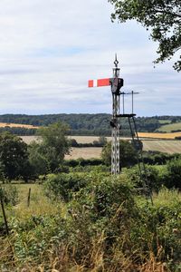 Old railway signal on field against sky