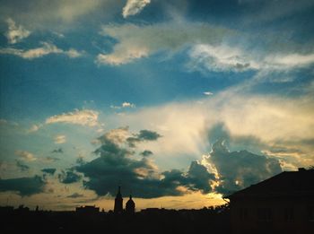 Low angle view of silhouette buildings against cloudy sky