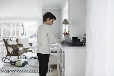 Boy cleaning cabinet in living room at home