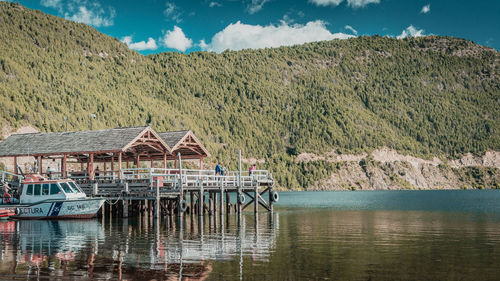 House by lake against sky