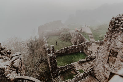 Destroyed old stone castle with fog with walls and stairs with tower on cloudy day