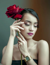 Close-up of woman holding rose against white background