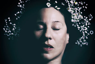 Close-up of woman with closed eyes against black background