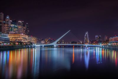 Puente de la mujer over river in city at night