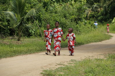 Full length of father with children walking on palm tree
