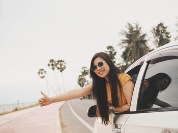 Portrait of smiling woman gesturing in car on road