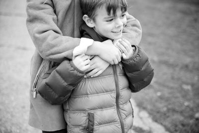 Midsection of sister embracing brother while standing on field