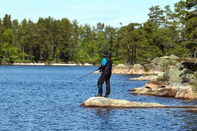 Full length of man fishing in forest against sky