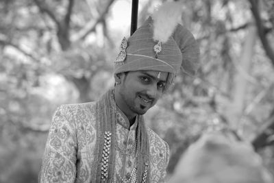 Portrait of young man smiling on his marriage against tree