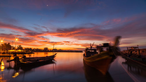 Boats moored in sea against sky during sunset