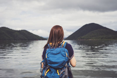 Rear view of man standing on mountain against sky