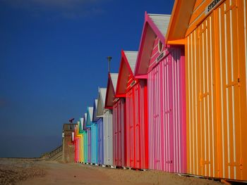Colorful huts at beach against blue sky on sunny day