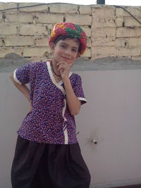 Portrait of smiling boy wearing traditional clothing while standing against wall