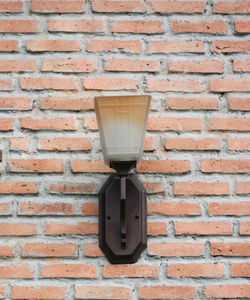 Close-up of electric lamp on brick wall