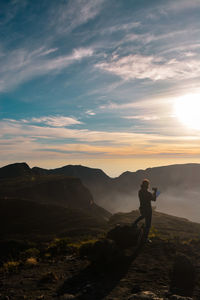 Man standing on mountain against sky during sunset