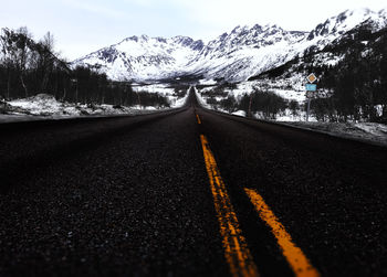 Surface level of empty road against snowcapped mountains