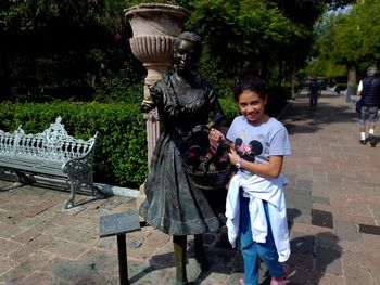 Full length of woman holding umbrella on bench in park