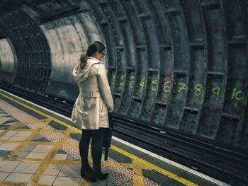 Rear view of woman standing at railroad station