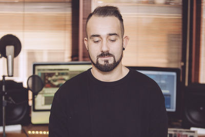 Handsome man looking down while standing in recording studio