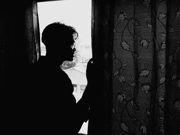 Silhouette man standing by window at home