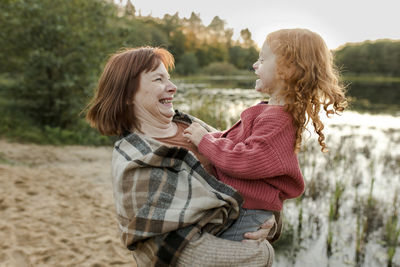 Happy grandmother playing with granddaughter by lake