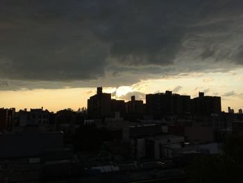 Buildings in city against dramatic sky