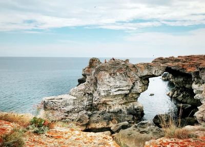 Rock formation by sea against sky