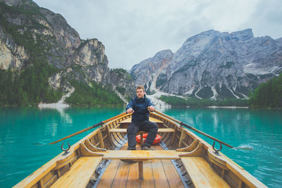 Man rowing boat in lake against mountains