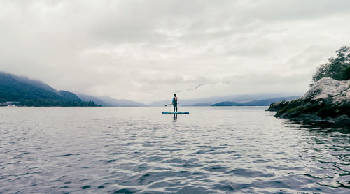 Rear view of man in sea against sky