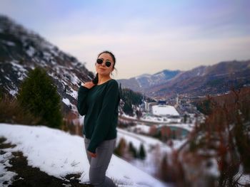 Young woman standing on mountain against sky