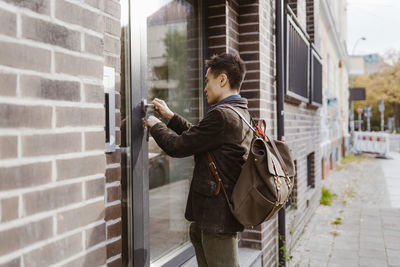 Man wearing backpack while locking apartment door
