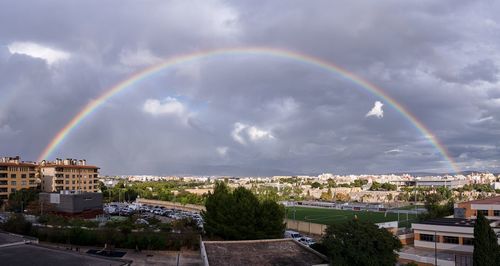 Rainbow over cityscape against sky