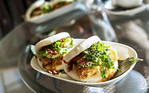 Two vegan bao sandwich with tofu, kimchee and parsley on glass table in cafe healthy vegetarian food