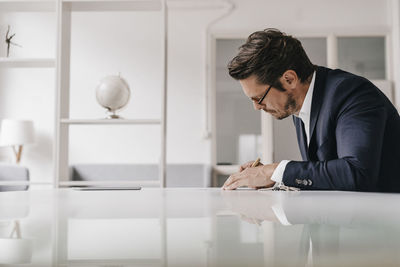 Businessman at table writing in notebook