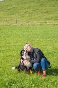 Mature woman embracing dog while crouching on grass