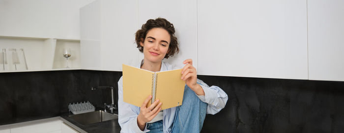 Portrait of young woman standing against wall