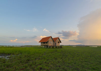 House on field against sky during sunset