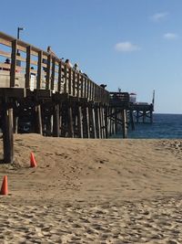 Wooden posts on beach by sea against sky