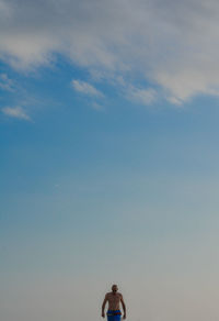 Shirtless man standing against sky