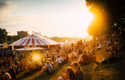 Group of people at music concert against sky during sunset