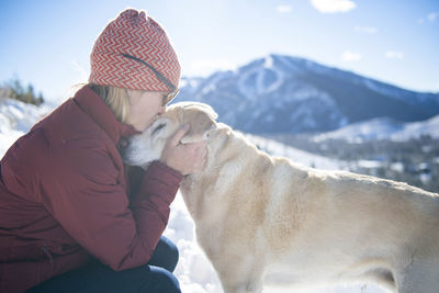 A woman giving her dog a loving kiss.