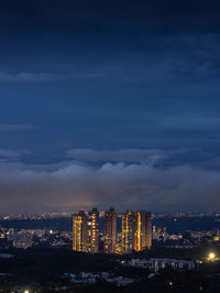 Illuminated buildings in city against sky at night