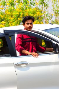 Portrait of young man sitting on car