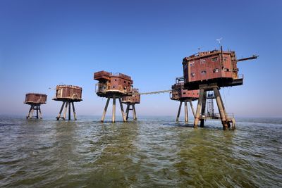 Lifeguard hut in sea against clear blue sky