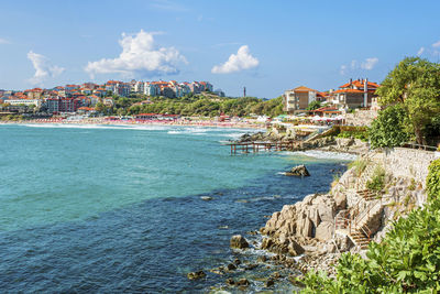 Scenic view of sea by townscape against sky