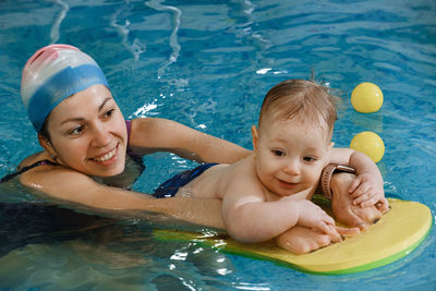 Early age swimming in pool. baby boy trained to swim in water coach woman in indoor swimming pool  