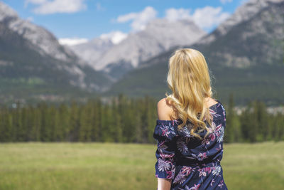 Rear view of woman standing on field against sky