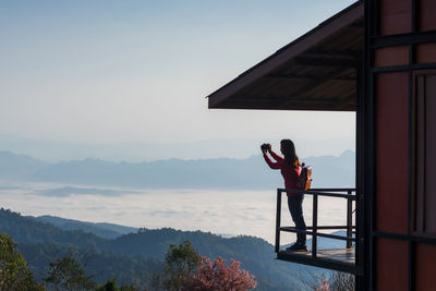 Rear view of woman standing on mountain against sky