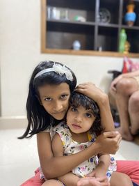 Portrait of girl embracing sister while sitting at home